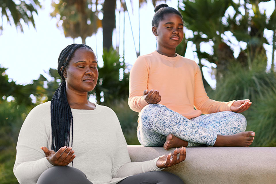 A woman and her son meditating while sitting outside