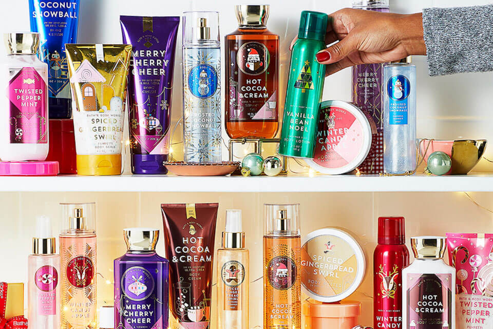 Bath and Body works products sitting on two shelves, and a hand is reaching in to pick up one.