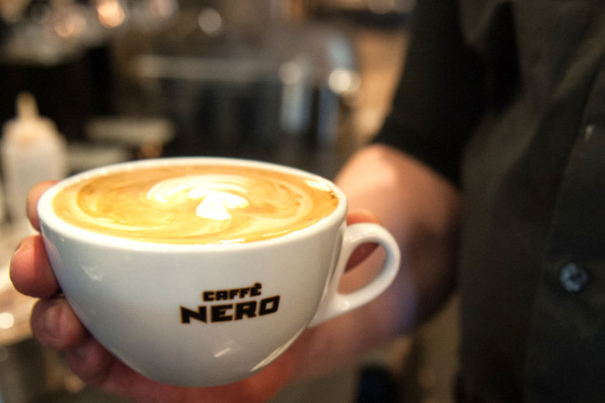 A cup of coffee with Latte Art on the top. It's inside of a white mug that has the Caffe Nero logo on it.