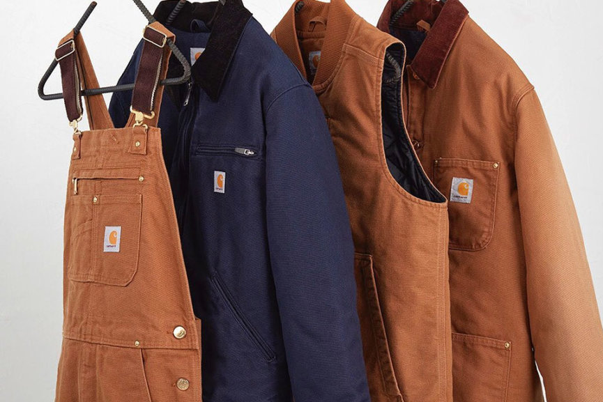 A pair of overalls, and various jackets hanging on a rack.