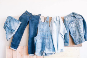 Various jeans and denim clothing hanging up on a wall