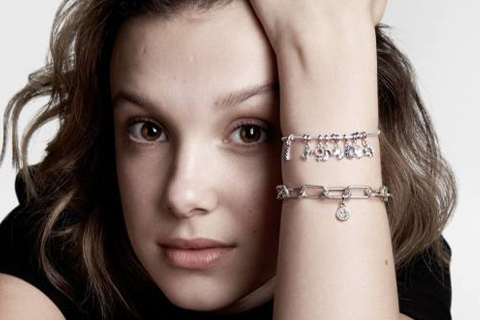 A close up of a girls face, her arm is visible with two bracelets on it.