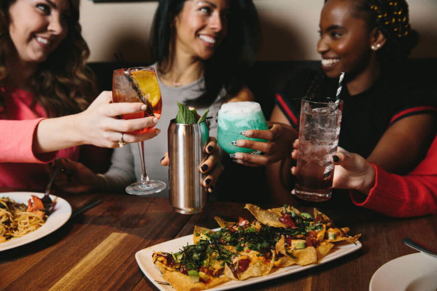 A group of woman toasting over a plate of appetizers